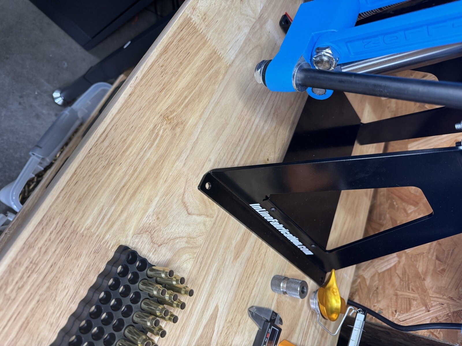 A progressive press mount resting on an unmarked wooden bench before its mounting holes were drilled