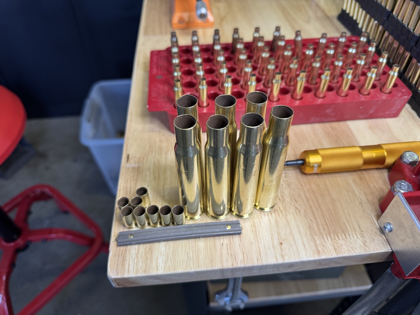 A loading block of cleaned 5.56 cases beside larger cases, smaller pistol cases, and a stripper clip