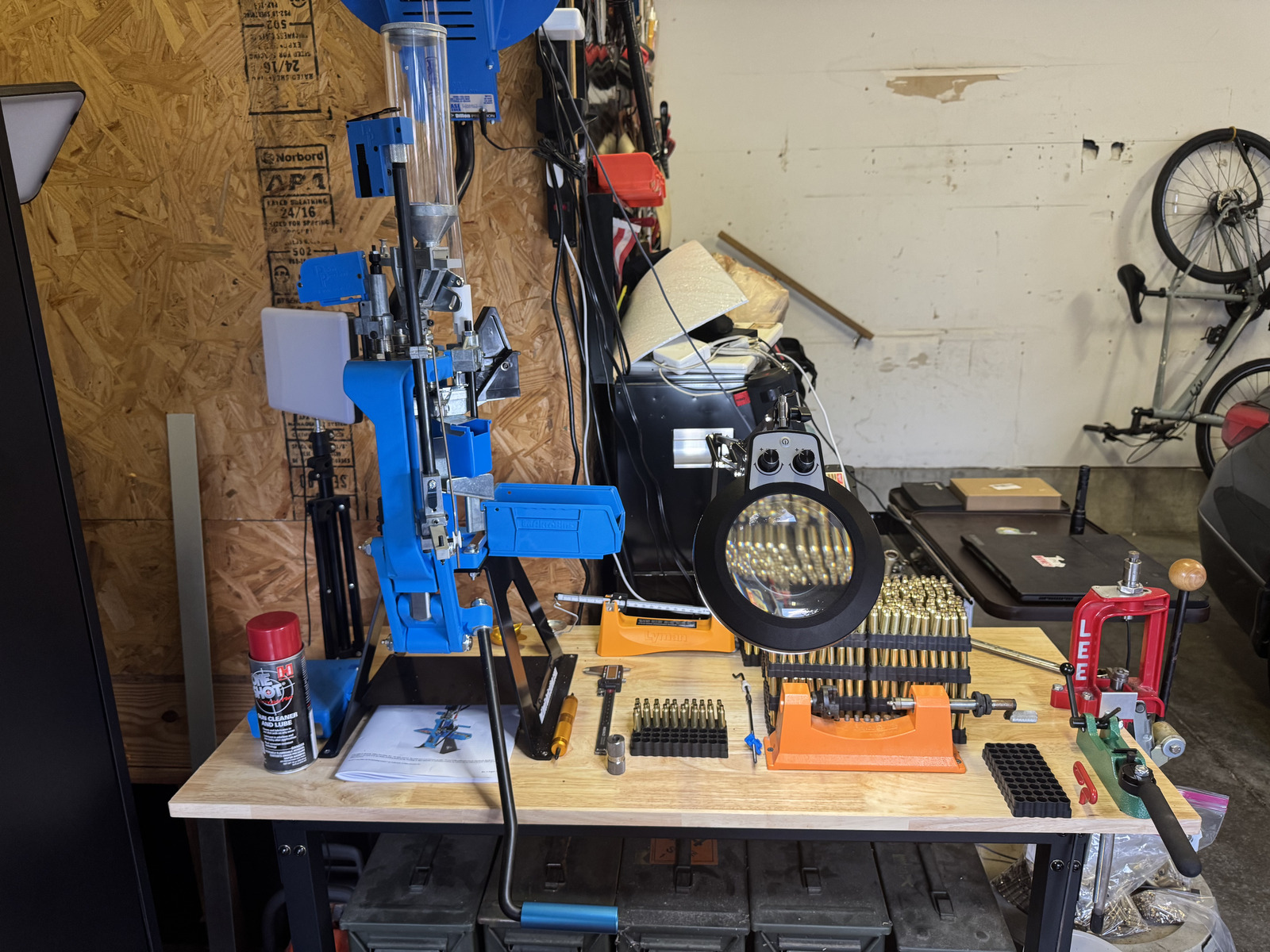The current reloading bench with the Dillon, magnifier, loading blocks, Lyman preparation center, Lee press, and RCBS swager visible together